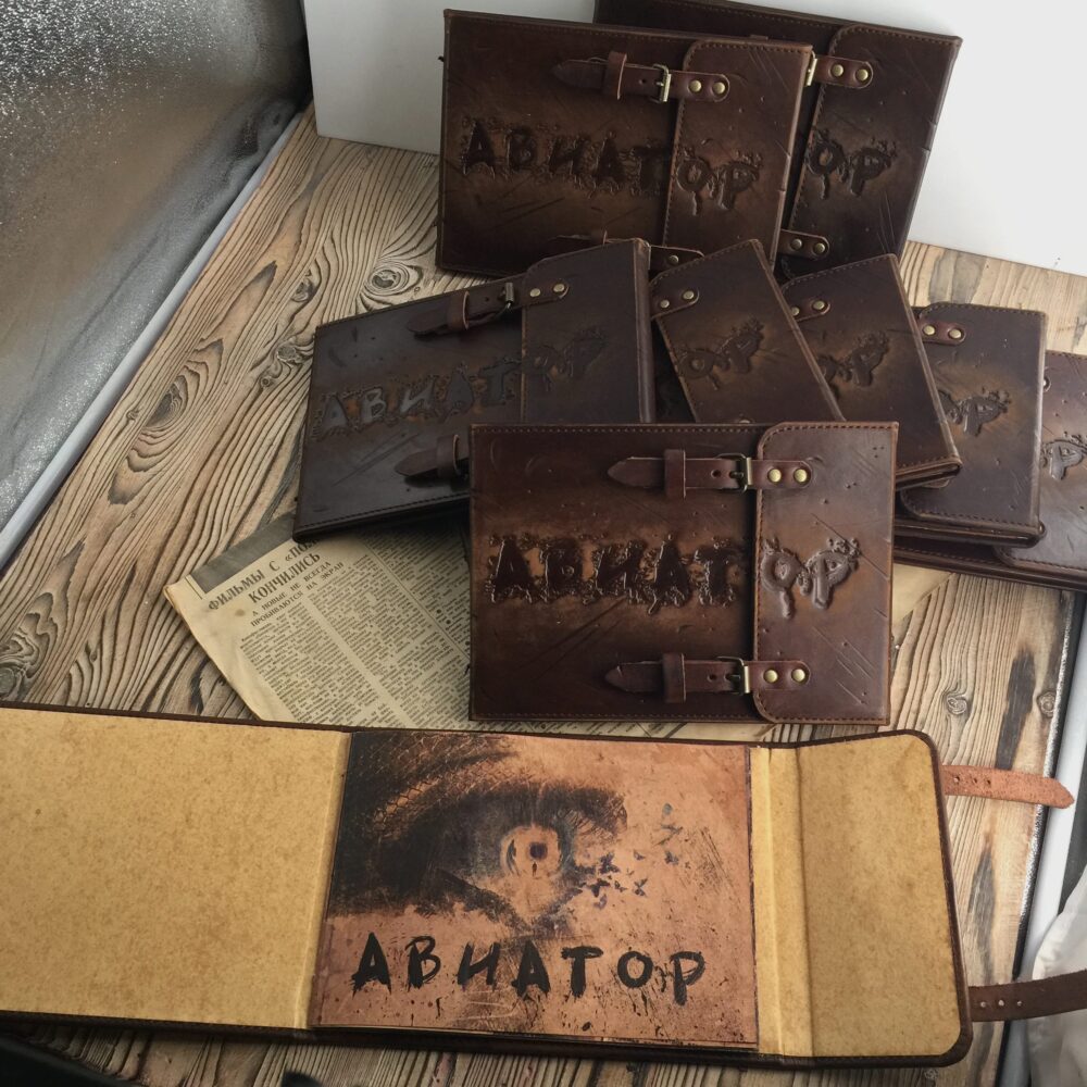 Стопка одинаковых кожаных презентационных книг с тиснёной надписью «Авиатор»
